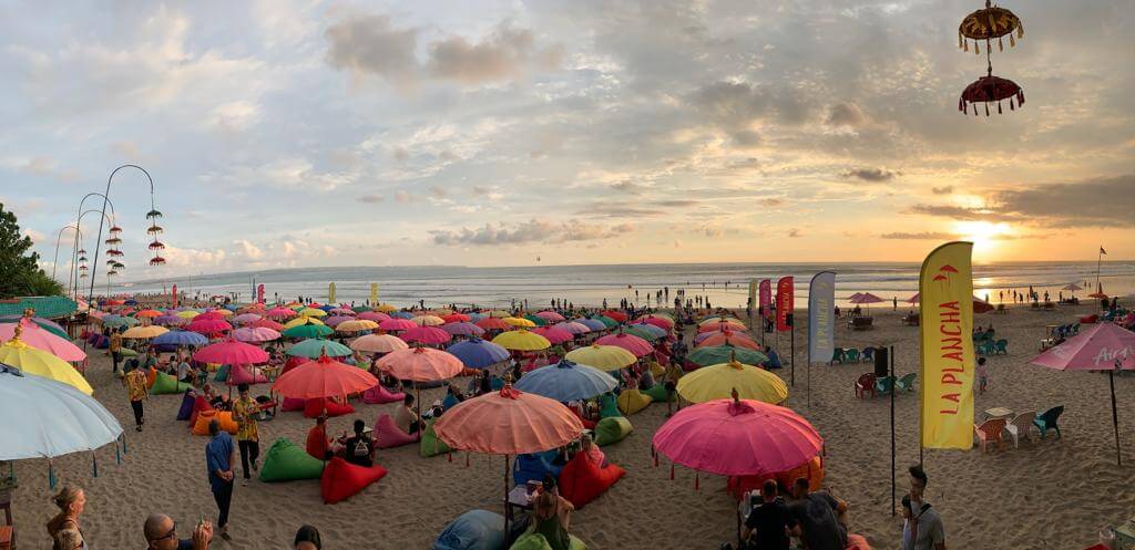 Zahlreiche bunte Sonnenschirme auf dem Strand mit vielen Menschen