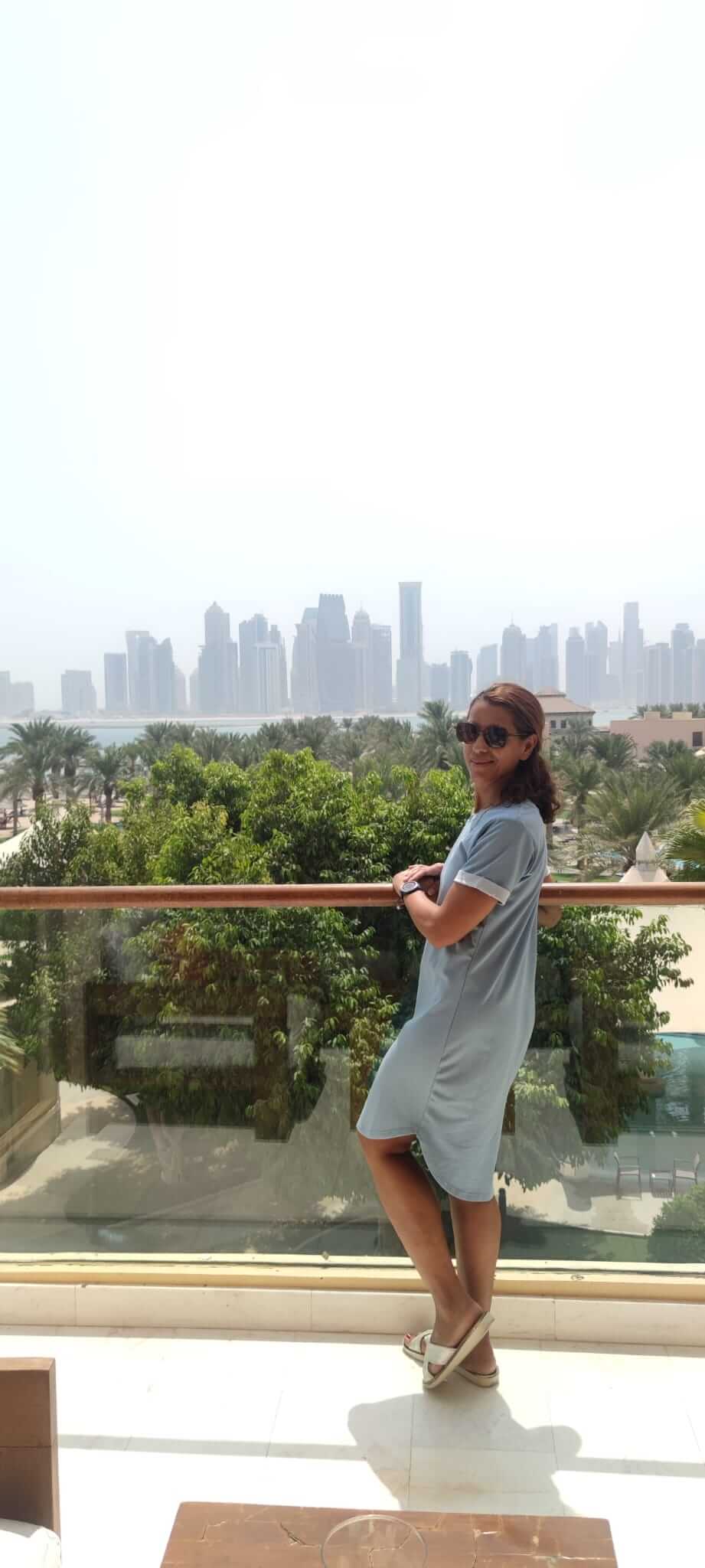 Hala steht auf einem verglasten Balkon und im Hintergrund ist eine Skyline aus Wolkenkratzern